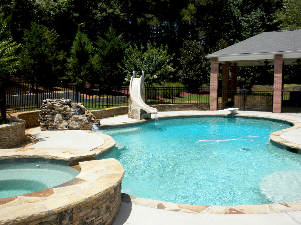 Pool with a slide, rock waterfall and stone spa
